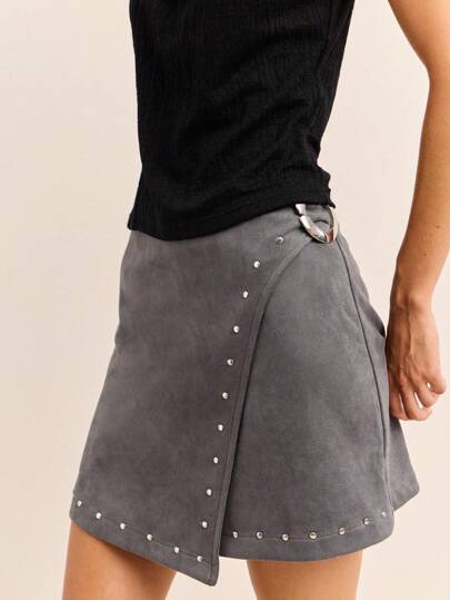 Nöista Cette mini-jupe  vert foncé présente un design asymétrique enveloppant avec des accents en clous argentés et une ceinture à double anneau, combinant le streetwear audacieux au style vintage années 2000, parfait pour la mode féminine de l'automne et de l'hiver.