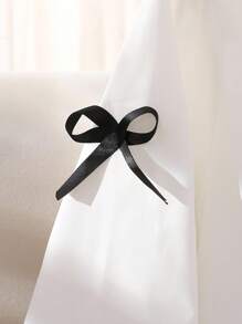 女式白色衬衫裙，学院风泡泡袖，刺绣领口，袖口饰有黑色蝴蝶结。荷叶边下摆设计增添甜美优雅气息，适合休闲、约会等场合，春秋冬皆宜