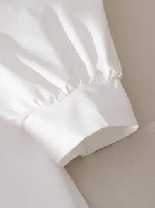 女式白色衬衫裙，学院风泡泡袖，刺绣领口，袖口饰有黑色蝴蝶结。荷叶边下摆设计增添甜美优雅气息，适合休闲、约会等场合，春秋冬皆宜