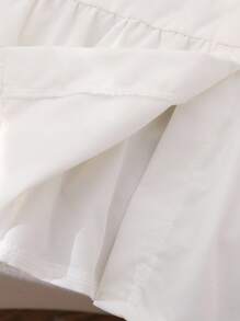 女式白色衬衫裙，学院风泡泡袖，刺绣领口，袖口饰有黑色蝴蝶结。荷叶边下摆设计增添甜美优雅气息，适合休闲、约会等场合，春秋冬皆宜