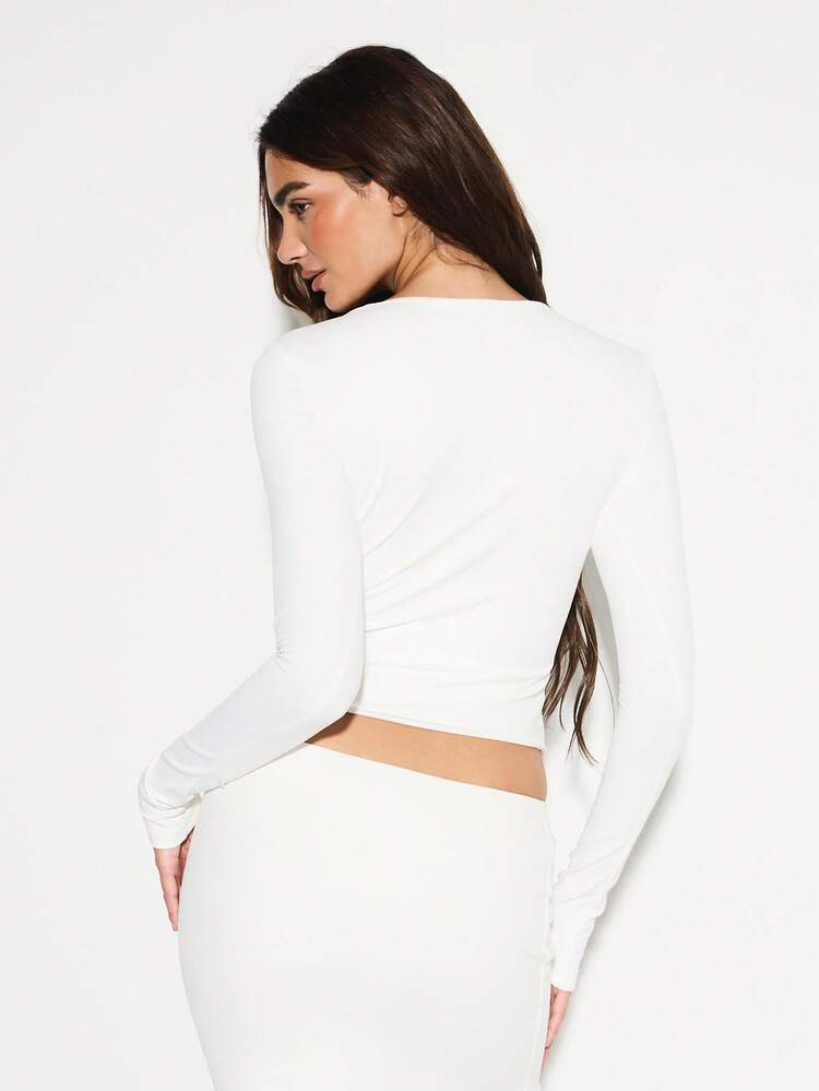 KIZN Top court à manches longues avec découpe en forme de trou de serrure et boucle dorée à la taille. Déclaration de mode pour l'hiver, l'automne, les soirées et les fêtes