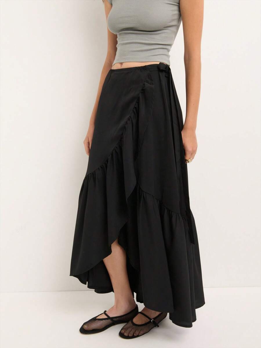 Nöista This Black Maxi Skirt Features An Asymmetrical Wrap Design With A Side Tie And Subtle Ruffle Hem, Blending Vintage Elegance With Y2K Streetwear Vibes, Perfect For Fall And Winter Women's Fashion.