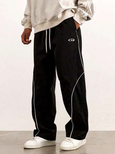 Manfinity Sport Corelite Långa sportbyxor i vävt tyg för män med dragsko i midjan och snygg bokstavsdesign i svarta och vita träningsbyxor, säckiga gymkläder för män, atletiska byxor, träningsbyxor