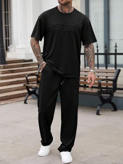 Manfinity Homme مجموعة قميص وبنطلون كاجوال للرجال بلون أحادي مع طباعة حرفية مُنقّرة، مجموعة رجالية صيفية سوداء قطعتين، بنطلون رياضي وقميص رجالي مجموعة ملابس الشارع الصيفية للرجال، بدلة رياضية رجالية سوداء