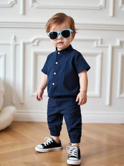 Souflis Souflis Conjunto de 2 piezas para bebés niños en color azul plaid fresco para primavera y verano. La Top de manga corta con cuello abierto muestra un aspecto elegante, combinada con pantalones cortos a juego para un atuendo armonioso. Los patrones mínimos resaltan el estilo sencillo y de moda. Adecuado para juegos al aire libre para exudar vitalidad soleada, ocio en casa para comodidad, actividades deportivas para flexibilidad y ocasiones de fiesta para convertirse en un joven caballero encantador.