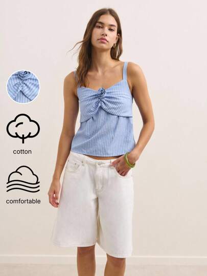 Nöista 这款蓝色细条纹吊带背心可为秋季女装或返校风格增添一抹俏皮气息。胸部饰有可爱的蝴蝶结，配有细肩带，可轻松搭配裙子、牛仔裤或开衫，打造青春活力造型，是秋季分层穿着的完美之选。
