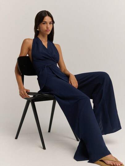 Nöista 这款精致的海军蓝露背连体裤，定会让您眼前一亮！裹身式紧身胸衣和修身阔腿廓形，使其成为秋季女装的完美之选，无论是打造优雅的商务休闲造型，还是出席特殊场合，都能提升您的时尚品味。轻松随性，时尚百搭，是秋季夜生活和冬季时尚女性的理想之选。