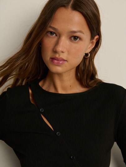 Nöista Nöista Black Rib-Knit Top With A Bold Asymmetrical Neckline Cut-Out And A Slim Diagonal Button Placket That Slices Across The Bodice, Subtly Cinching The Waist. Long, Fitted Sleeves Balance The Cropped-At-Hip Length, Creating A Sleek, Paris-Meets-Tokyo Vibe. Style It With High-Rise Denim For Downtown Days, Leather Minis For Night, Or Layer Under A Sharp Blazer For Office Edge-Minimalist, Architectural, And Irresistibly Cool All Season.