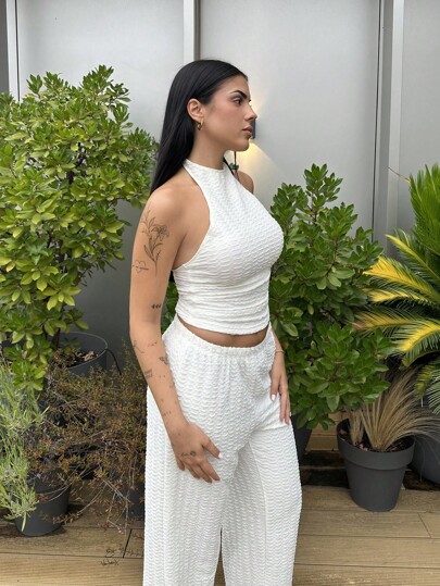 Lucia Bellido Conjunto de suéter corto beige y pantalones anchos de mujer, sin mangas con cuello halter y atuendo casual