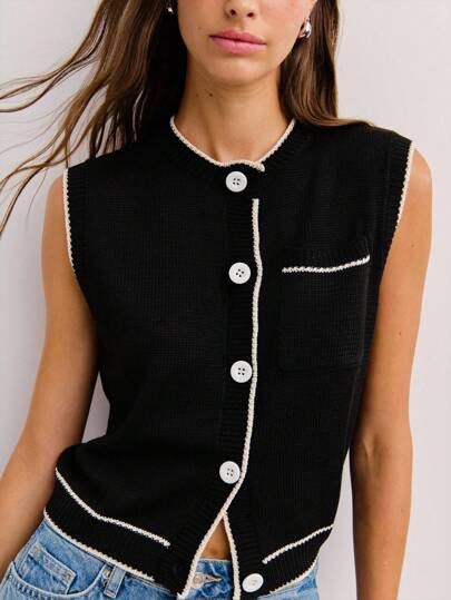 Nöista 这款黑色无袖开衫边缘有白色滚边，白色纽扣形成对比，胸前有一个小口袋，融合了复古魅力和老钱风格，是秋冬季女性街头服饰的理想选择。