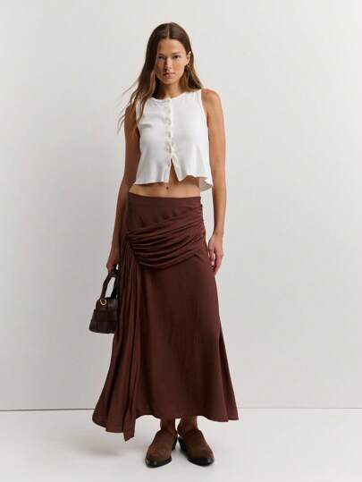 Nöista 秋季必备色系棕色，易于与不同颜色单品搭配。裙身采用A字形剪裁，修饰下半身线条，兼具包容性和优雅气质，适合追求个性设计感与舒适质感的都市女性。可用于日常休闲旅行、上班等场合，搭配针织上衣或衬衫，凸显自然沉稳的气质。