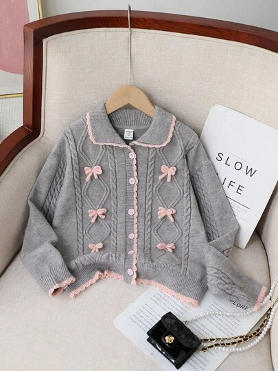 这款女童加厚灰色粉色撞色开衫，采用柔软弹力抓绒面料，适合外出、聚会和休闲穿着，是秋冬季女童开衫毛衣的理想之选。这款开衫采用酷炫的灰色手工编织双层羊毛蝴蝶结针织而成，饰有菱形图案，粉色下摆、袖口和领口更添精致。它有6颗纽扣，是一款长袖长领开衫。这款毛衣柔软舒适，适合秋冬季节穿着，日常穿着、旅行、度假和居家皆宜。是孩子们玩耍和返校季的完美之选。