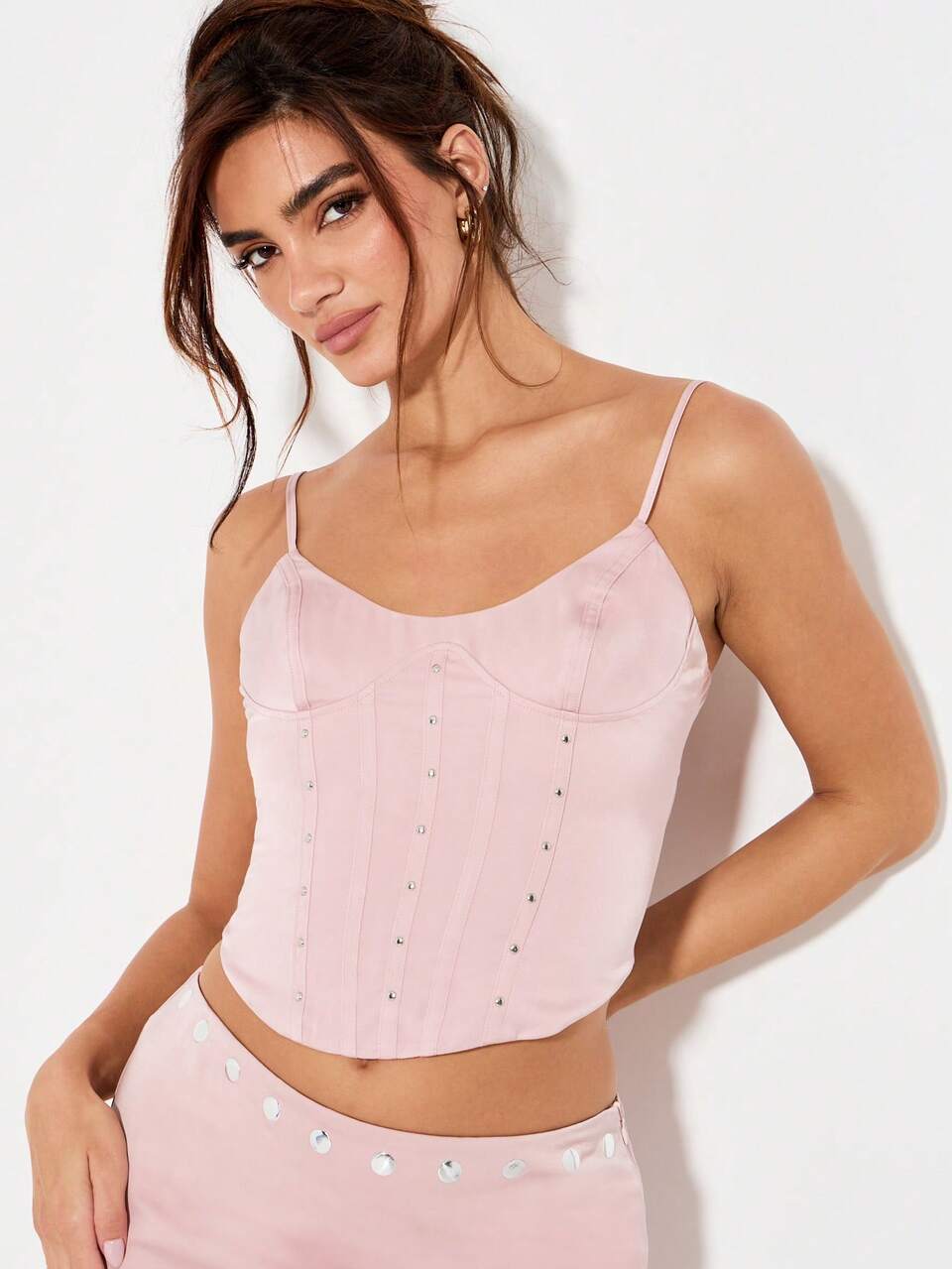 Top corset en satin clouté avec mini-jupe assortie. Crop top de soirée/club avec bretelles spaghetti, détails de boutons métalliques et fermeture éclair au dos. Bustier