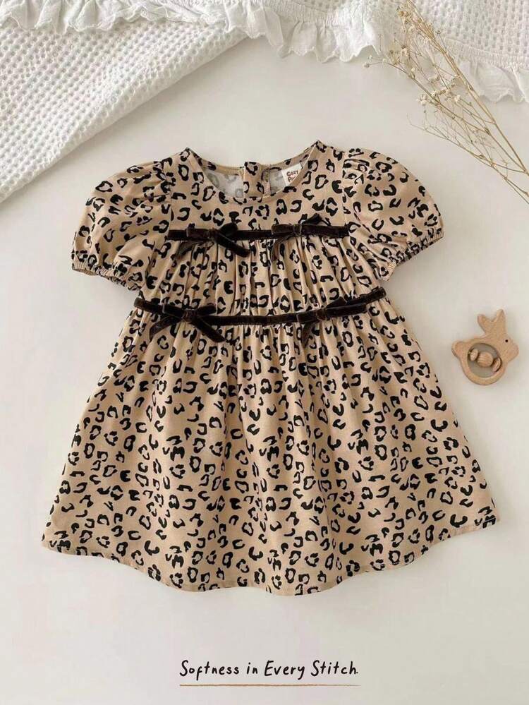 Cozy Pixies Đầm bé gái họa tiết da báo phối màu, viền bèo nhún, cổ tròn, tay phồng, eo thắt. Đầm da báo cho bé sơ sinh. Đầm màu mơ cho bé gái. Đầm họa tiết động vật cho bé gái. Đầm tay ngắn cho bé gái. Đầm màu nâu. Quần áo cotton cho bé gái. - Màu be - Xem 3