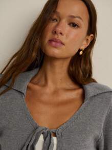Nöista Áo khoác cardigan dệt kim dáng ngắn màu tím nhạt với cổ chữ V hở, cổ áo xẻ mềm mại và ba dây buộc phía trước. Cổ tay áo bo gân và cạp chun rộng tạo hiệu ứng tôn dáng. Hoàn hảo cho mùa thu, những buổi học tập hoặc những buổi hẹn cà phê thân mật. - Xám - Xem 4