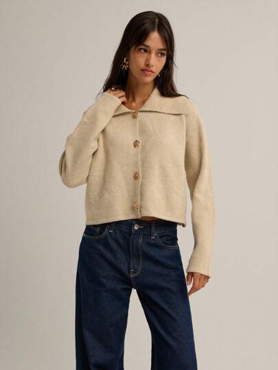  这款Nöista米色针织开衫饰有金色花卉纽扣，独特的超大领口设计，质地柔软舒适。保暖又时尚，易于叠穿，为日常穿搭增添一丝优雅气息。