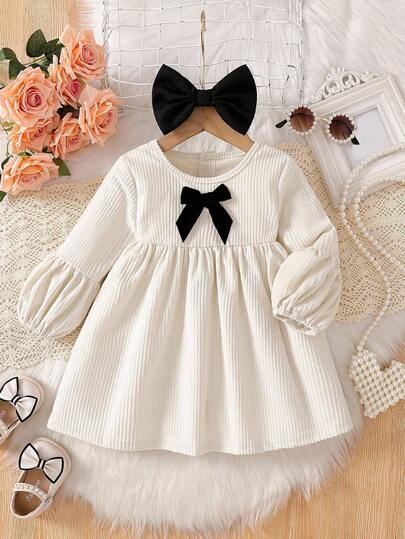 SHEIN 女婴纯色圆领3D蝴蝶结灯笼袖A字裙，搭配同色系3D蝴蝶结头饰。宽松灯笼袖设计搭配经典A字廓形，打造时尚优雅造型。无论是日常休闲装、公园郊游、生日派对还是节日庆典，这款连衣裙都能让您的小宝贝在任何场合都闪耀公主光彩。