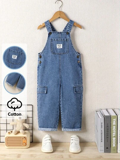 SHEIN Playful Pals 男童牛仔背带裤，复古美式学院风休闲装推荐，中蓝色水洗牛仔布，前袋上的品牌贴片增添酷感，侧面有仿口袋，合身舒适的廓形，反向下摆设计，可调节肩带，衣橱必备牛仔背带裤