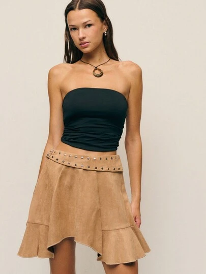 Nöista 这款驼色迷你裙采用柔软的仿麂皮绒面料，搭配精致的不对称裙摆。饰有铆钉的腰带更添现代时尚感，是搭配冬装和保暖内搭的理想之选。无论是圣诞节、新年还是感恩节，它都能完美融入各种场合，为女士的冬季衣橱增添优雅百搭的单品。搭配黑色上衣、厚毛衣或正式外套，轻松打造节日或日常造型。