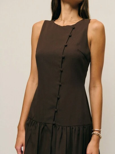 Nöista 这款深棕色无袖低腰迷你连衣裙，正面饰有一排布包纽扣。其俏皮的廓形融合了复古魅力和现代简约主义，完美适用于从白天到夜晚的各种造型。