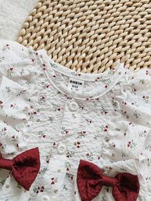 SHEIN Vintaside Kids فستان طفلة حديثة الولادة بياقة مستديرة، مطرز بطبعات كرزية كرتونية، أكمام طويلة، فيونكة حمراء، أنيق وجذاب، مناسب لجميع الفصول، طراز جديد - ابيض واحمر - مشاهدة 5