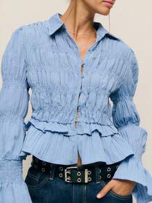 Nöista 精致的褶饰纽扣衬衫，采用轻盈的褶皱棉布制成，上身采用褶皱设计，下摆饰有精致的荷叶边，泡泡袖收拢，形成褶饰喇叭袖口和柔软的尖领。透气面料带来透气舒适感和微妙的弹性，塑造纤细腰身、柔美廓形，是春季造型的完美之选，也是秋季轻松过渡的叠穿之选。 - 藍色 - 查看 7
