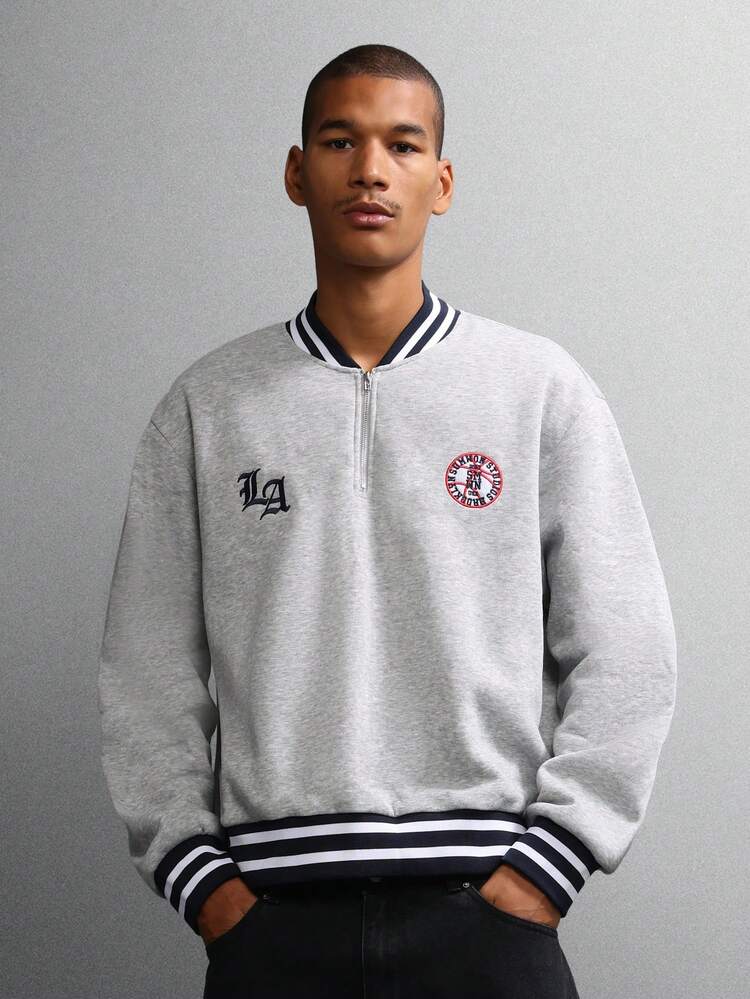 바시티 트림과 로고 디테일이 있는 하프 지퍼 스웨트셔츠