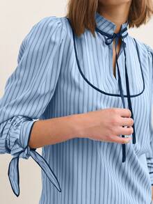 Nöista Blusa de manga larga a rayas con ribete de contraste y un suave cuello con volantes - Una elegante y chic blusa de otoño/invierno. Las rayas verticales y un cuello con lazo le dan un toque refinado y ligeramente vintage, mientras que las suaves mangas abullonadas y los puños recogidos crean una silueta pulida ideal para combinar con otras prendas.