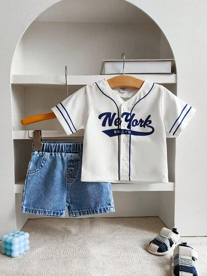 男童时尚百搭白色棒球夹克短袖上衣和浅蓝色牛仔裤套装。这款白色短袖棒球衫饰有蓝色花卉图案和深蓝色标志，营造出休闲做旧的感觉。柔软舒适，可爱的休闲户外运动风格，适合春夏季户外玩耍、度假、日常穿着和旅行。