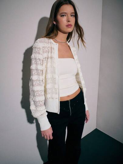 Nöista 这款精致的开衫采用水平蕾丝镶板和荷叶边饰边，为优雅的女式衬衫增添了立体质感。采用修身剪裁，罗纹袖口和下摆设计，将休闲衬衫风格与精致感融为一体，非常适合高级日装或晚间分层穿着。