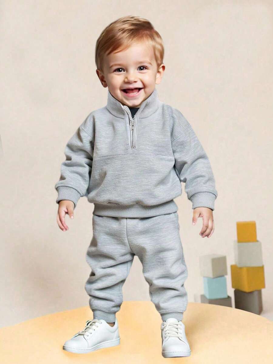 SHEIN 1 conjunto de niño pequeño de pantalón de cintura elástica lisa y sudadera con cremallera media abierta de unicolor de manga larga. Un conjunto cálido y cómodo adecuado para que los niños usen en otoño y primavera. Este conjunto no solo es adecuado para salir, sino también para usar en casa. Este versátil y duradero conjunto es adecuado para varias ocasiones en la vida diaria de los niños pequeños, manteniéndolos a la moda y cómodos en las temporadas de primavera y otoño. - Gris - Ver 1