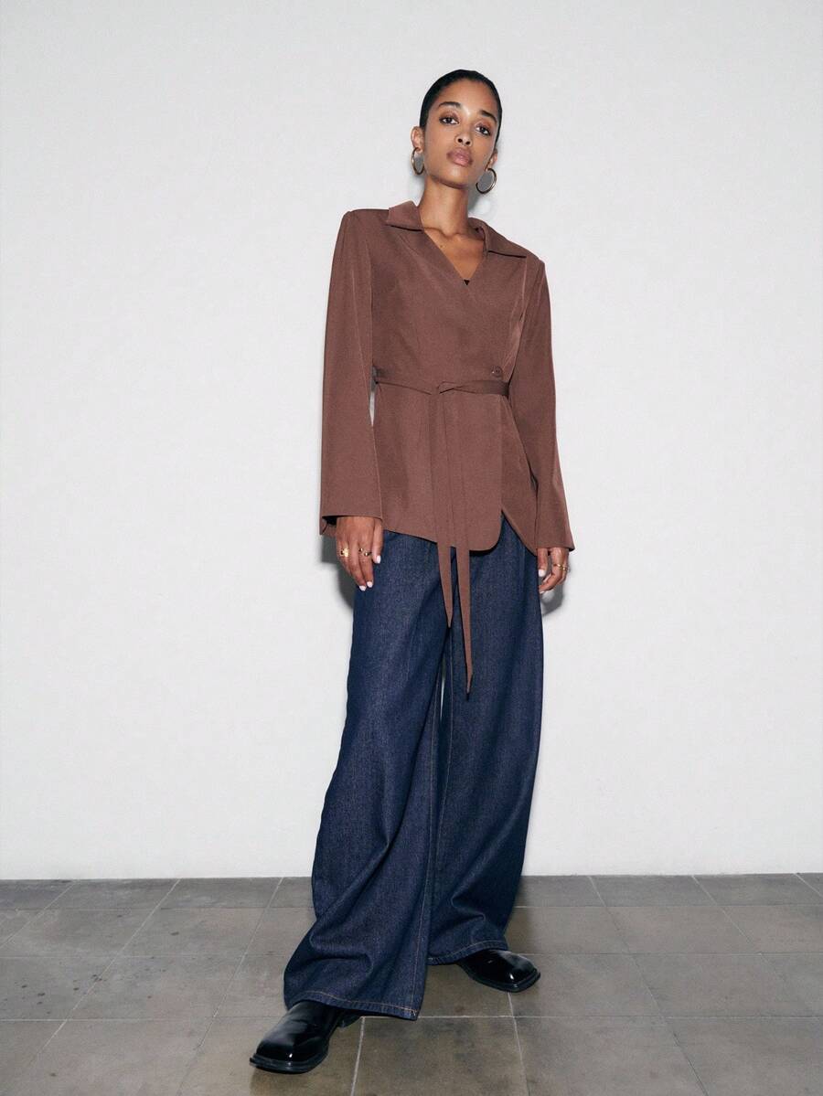 Nöista Elegante und vielseitige braune Wickeljacke mit schmeichelhafter Taillengürtel-Passform und Reverskragen. Ein stilvolles Kleidungsstück, perfekt für Büro, Abendgarderobe oder festliche Winteroutfits. Ideal zum Kombinieren mit Winterkleidung zu Weihnachten, Silvester und Thanksgiving – verleiht jedem Look eine elegante Note.