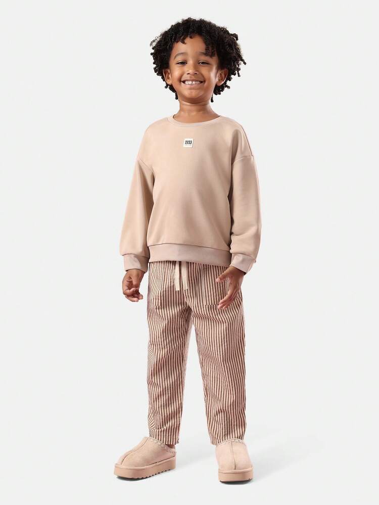 レトロなオレンジソーダのスウェットシャツとストライプパンツ