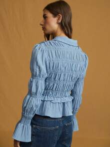 Nöista 精致的褶饰纽扣衬衫，采用轻盈的褶皱棉布制成，上身采用褶皱设计，下摆饰有精致的荷叶边，泡泡袖收拢，形成褶饰喇叭袖口和柔软的尖领。透气面料带来透气舒适感和微妙的弹性，塑造纤细腰身、柔美廓形，是春季造型的完美之选，也是秋季轻松过渡的叠穿之选。 - 藍色 - 查看 2