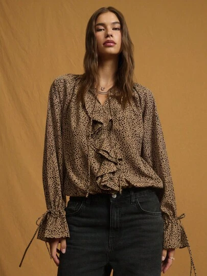 Nöista 这款灰褐色和黑色动物纹印花衬衫采用飘逸的廓形、系带领口和荷叶边前襟设计，非常适合大胆的秋季造型、俏皮的冬季叠穿，或现代女性的休闲装扮。