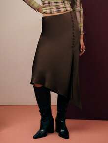 Nöista Cette jupe brune raffinée présente un ourlet asymétrique et des détails de boutons sur le côté. Fabriquée en satin lisse, elle tombe magnifiquement et est idéale pour les tenues de vacances de printemps, les dîners de Thanksgiving ou les tenues d'anniversaire pour femmes. Elle se marie facilement avec des hauts chics pour femmes. - Tabac - Voir 1