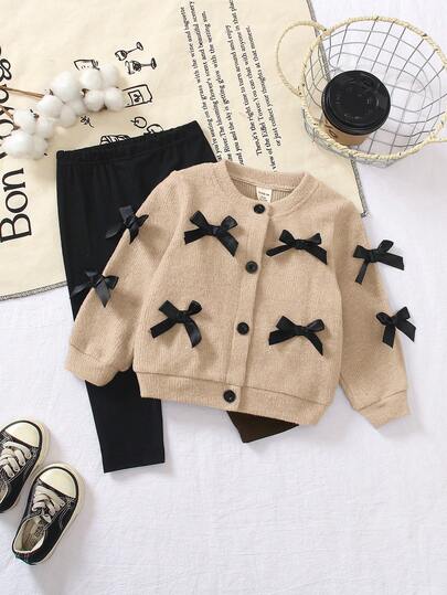 两件套韩版灰色蝴蝶结装饰长袖幼儿开衫。这款夹克正面中央纽扣开合，方便穿着，蝴蝶结装饰更添时尚优雅气息。搭配修身黑色长裤，适合外出、旅行和日常穿着。