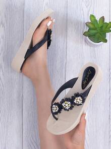 Sandalias tipo flip-flop de moda para mujer. La suela ofrece confort y suavidad a cada paso, mientras que las tiras negras están decoradas con tres elegantes flores adornadas con pedrería brillante en tonos dorado y blanco, dando un toque único y sofisticado. Su diseño ligero y cómodo es perfecto para llevar en el día a día, en la playa, vacaciones o simplemente para relajarte con estilo en casa. Las sandalias son fáciles de combinar con vestidos, shorts o jeans. - Negro - Ver 1