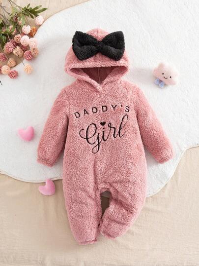 This Is A One-Piece Baby Girl's Cute Plush Pink Jumpsuit With Letter Patterns, A Contrasting Black Color, And A Large Black Bow. It's A Casual Zippered, Button-Down Jumpsuit For Autumn And Winter, Featuring A Large Bow And A Warm Design.