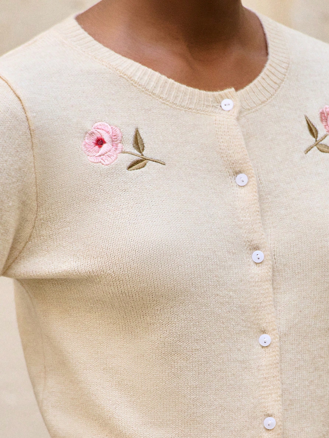 Beżowy dzianinowy kardigan z haftowanymi różami i zapięciem na guziki z przodu, wygodny na jesień i zimę