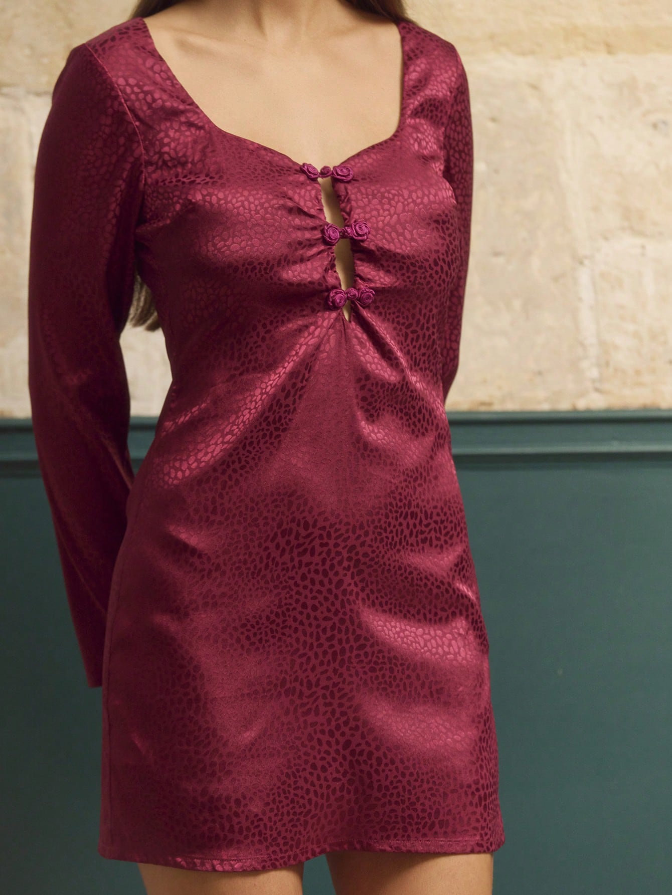 Robe mini ajustée en satin jacquard bordeaux avec découpe au niveau du décolleté et manches longues, élégante pour l'automne et l'hiver