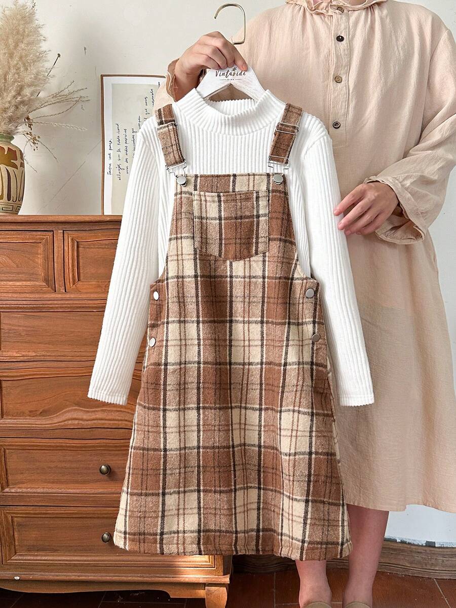 Vintaside Kids Completo da ragazza pre-adolescente composto da una maglietta a maniche lunghe con collo alto beige a righe e un vestito a canottiera in tweed a quadri per l'autunno e l'inverno. Le spalline del vestito a canottiera possono essere regolate in lunghezza e ci sono bottoni in vita per facilitare l'indossare e il togliere. Lo stile è retrò, semplice e da scuola. Il motivo a quadri è alla moda e versatile, rendendolo perfetto per un pomeriggio rilassante a casa, un'uscita e un picnic autunnale, la partecipazione a feste e eventi scolastici. - Cachi - Visualizzare 1