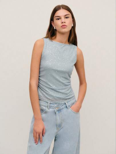 Nöista 这款灰色亮片上衣采用无袖设计，带有微妙的闪光，在光线下熠熠生辉。柔软弹力的面料带来舒适感和时尚感，使其成为春假派对、生日庆祝活动或女士春假服装系列中优雅装扮的理想之选。