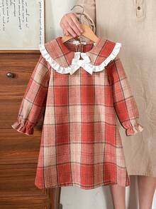 Vintaside Kids Váy len cổ búp bê kẻ caro màu nâu ấm áp, tay dài vừa phải, phong cách sinh viên ngọt ngào và cổ điển này có họa tiết caro đỏ cam và kaki, vừa cổ điển vừa dịu dàng. Được làm từ vải tweed thô, váy có độ dày vừa phải và dáng rộng. Ve áo rộng với viền ren trắng và nơ trắng ba chiều ở giữa, tạo điểm nhấn ấn tượng. Thiết kế khóa kéo phía sau giúp bạn dễ dàng mặc vào và cởi ra. Váy phù hợp để mặc đi học. - Nhiều màu - Xem 5