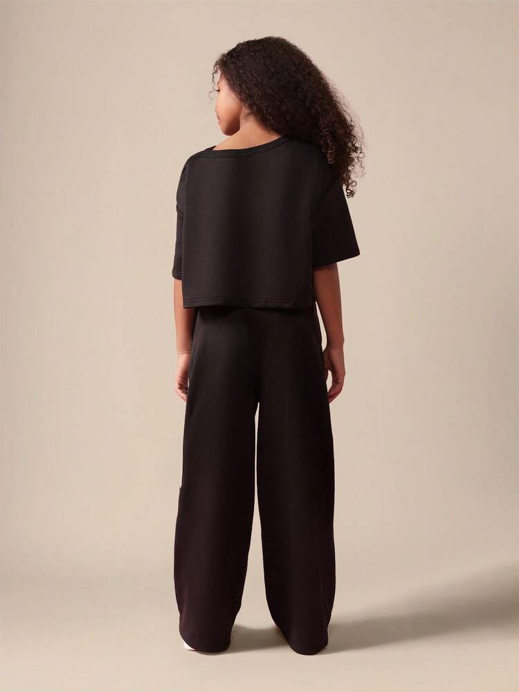 Top corto monospalla con diamanti e pantaloni a gamba larga