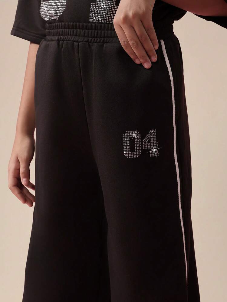 Top corto monospalla con diamanti e pantaloni a gamba larga