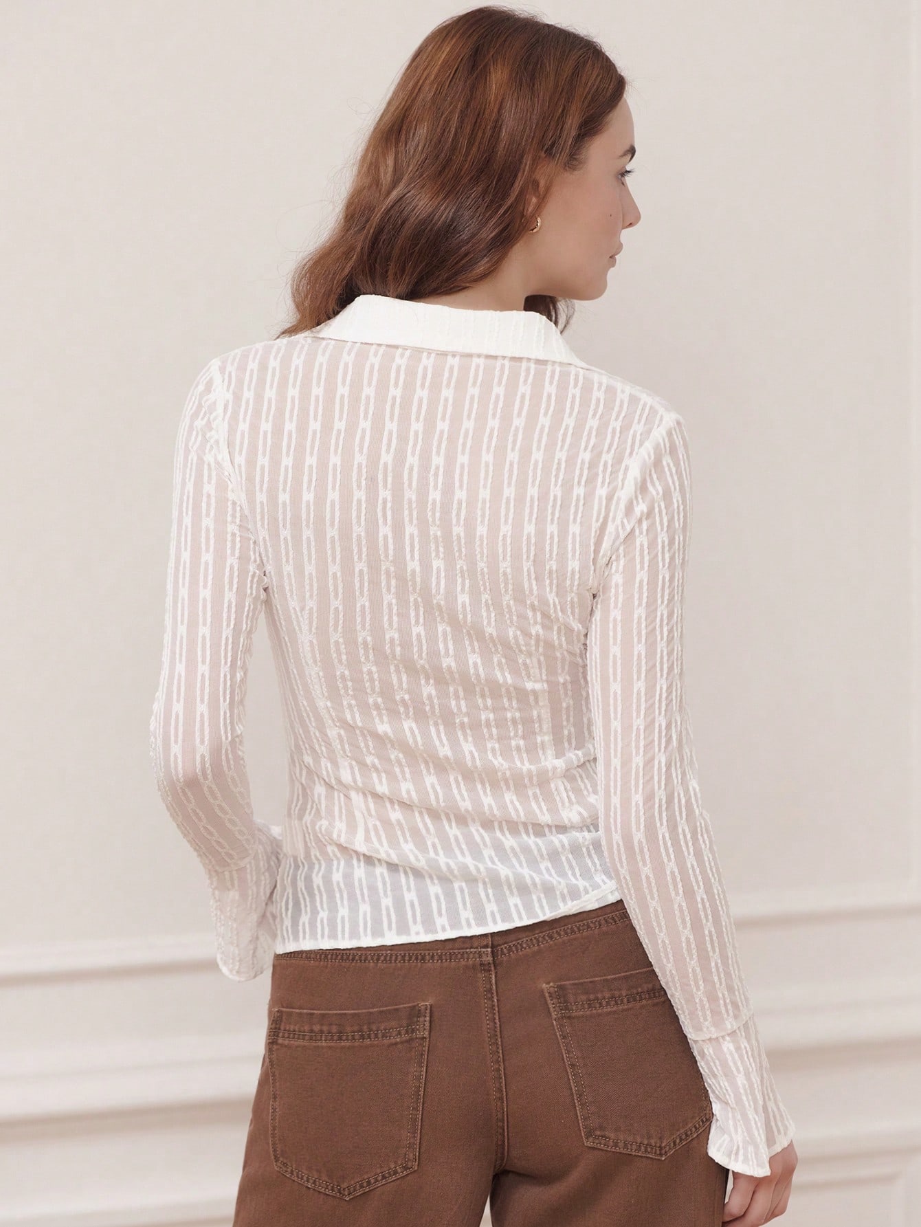 Camisa blanca ajustada y transparente con tela texturizada y puños acampanados