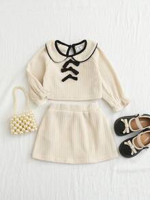 SHEIN 两件套女宝宝可爱甜美学院风时尚米色纯色罗纹纹理撞色黑色包边彼得潘领三蝴蝶结装饰长袖T恤套头衫和松紧腰A字裙两件套，柔软舒适，适合日常穿着、学校活动、秋冬季节。 - 白色 - 查看 10