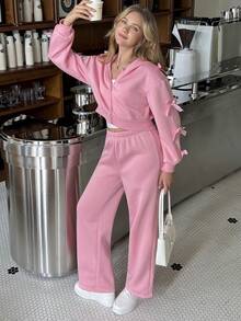 SHEIN 这款少女甜美风粉色连帽三件套，包含外套和裤子，采用柔软细腻的面料制成，带有连帽设计。服装上饰有立体蝴蝶结，增添俏皮感。腰部采用收腰设计，贴合身形。袖口采用常规款式，穿着舒适。内搭白色背心。 - 粉色 - 查看 3