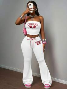 Slaydiva مجموعة بنطلون وكروب توب من قطعتين للنساء، تتكون من: كروب توب أكتاف بارزة ضيق من قماش مضفر وردي مع طباعة حرفية وفواكه كرز، مقترن مع بنطلون ضيق بخصر مطاطي وربطة حبل أحمر بطبعة الكرز، بأسلوب بوهيمي عصري مناسب للحفلات والشاطئ والأعياد، موديل ربيع/صيف 2025